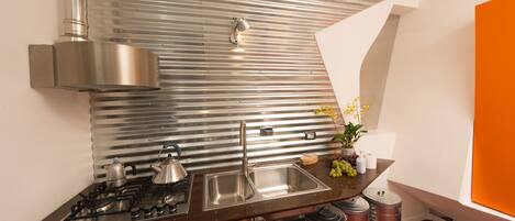 A modern kitchen with stainless steel appliances, a sink, and a backsplash of corrugated metal.