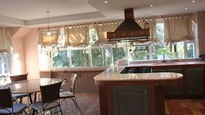 A kitchen with a central island, a dining table with chairs, and large windows with curtains. - APARTMENT IN VILLA WITH POOL IN THE SALT, HEATED, SPECTACULAR VIEW !!! (SANT'OMERO)