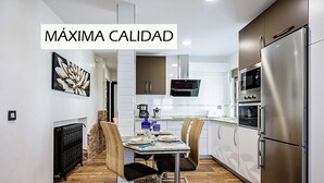 A modern kitchen with stainless steel appliances, a dining table with chairs, and a decorative wall piece. - Holiday Rental Salamanca 4pax WIFI and PARKING / OFFERS end of season (Salamanca)