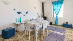 A room with a round table, white chairs, a patterned floor, and decorative wall art. - villa with views over Scopello (Scopello)