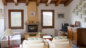A cozy living room with a fireplace, two sofas, a television, and a cabinet. - In September VENICE by train DOLOMITES by car in VENETO 9 Unesco sites 6 p (Cinto Euganeo)