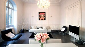 A spacious living room with a white sofa, black armchairs, a chandelier, and a large window. - Luxury, spacious, patio, near public gardens (Bordeaux)