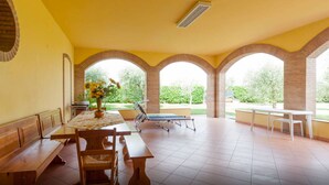 An outdoor patio with a wooden table and benches, a sun lounger, and a view of greenery. - TABACHERA x10 Country House Sirmione GARDA LAKE (pozzolengo)