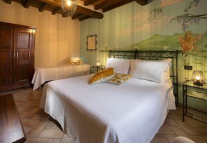A bedroom with two beds, a wooden wardrobe, and a mural on the wall.