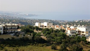 Ein Küstenwohngebiet mit modernen Gebäuden, freiem Blick auf das Meer und einer hügeligen Landschaft.