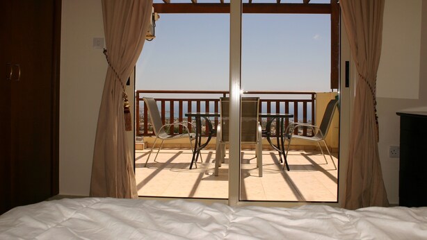 Ein Schlafzimmer mit Blick auf einen Balkon mit Stühlen und einem Tisch.