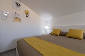 A bedroom with a bed, two pillows, a bedside lamp, and wall art.