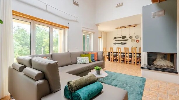 A spacious living room with a sofa, a dining area with a table and chairs, and a fireplace. - Casa EmCanto - Swimming pool, games room, cinema with capacity for 16 guests (Pombal)
