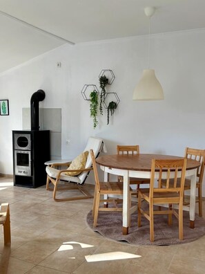 Een eethoek met een ronde houten tafel, vier houten stoelen, een hanglamp en hexagonale wanddecoraties met planten.