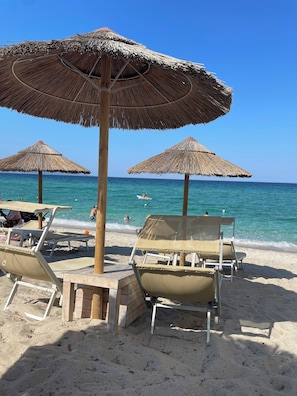 A beach with thatched umbrellas and lounge chairs. - Dimora Principe (Alghero)
