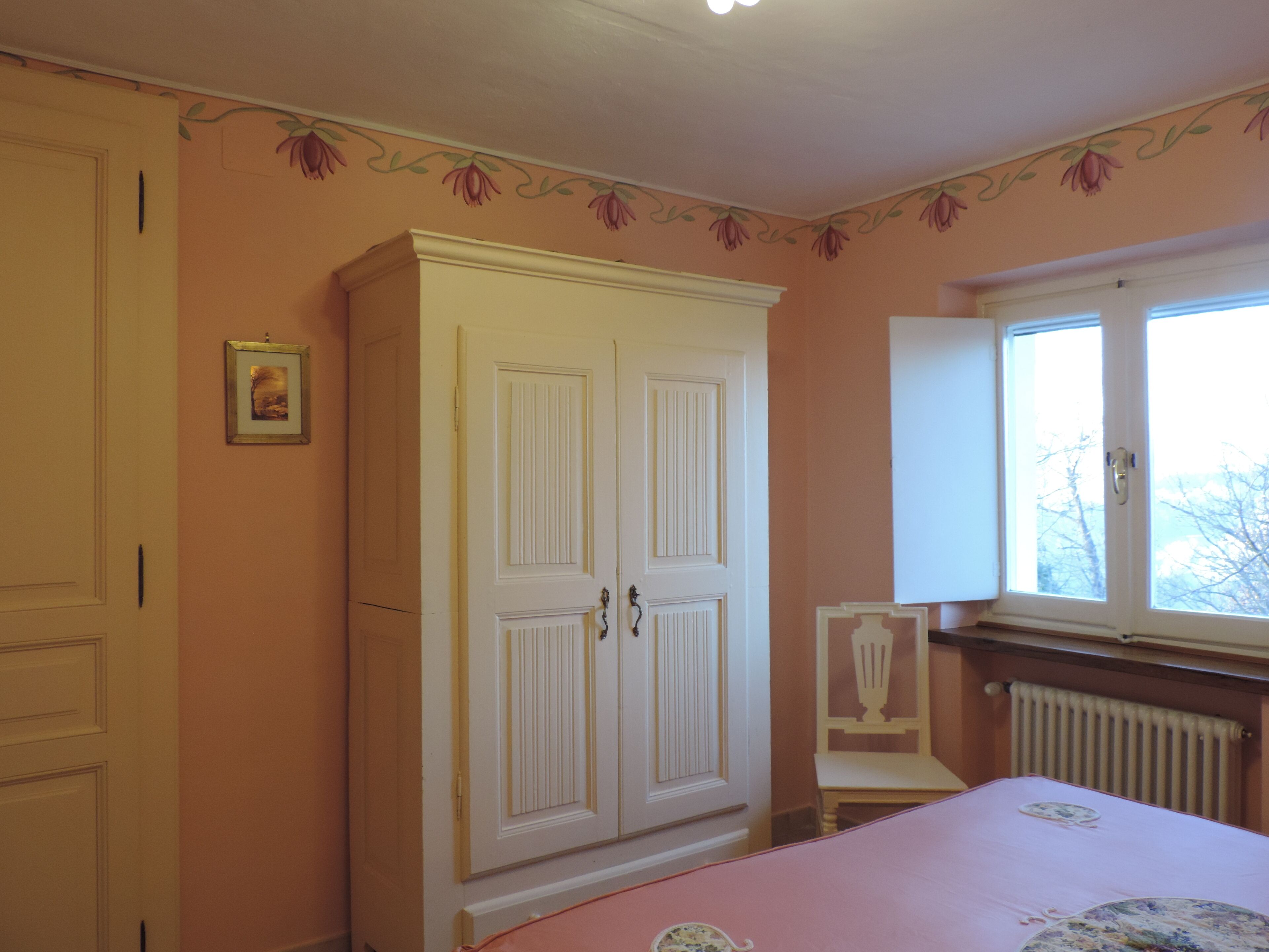 Une chambre à coucher avec un lit, une armoire, une chaise et une fenêtre.
