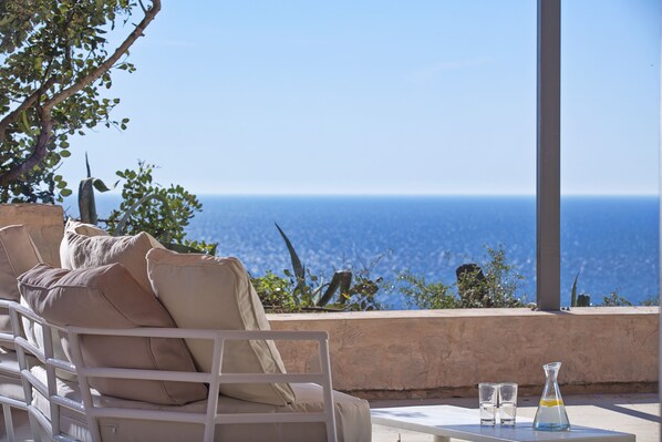 A white outdoor seating area with a view of the ocean.