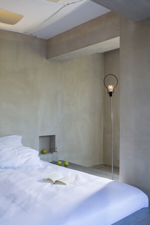 A modern bedroom with a large bed, a bedside table with apples, and a floor lamp.