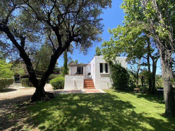 Une maison moderne à l’extérieur blanc, avec un escalier en bois menant à une porte et une pelouse bien entretenue.