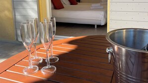 A wooden table with glasses and a metal bucket, leading to a bedroom with a bed, pillows, and a lamp. - VILLA VERDI D AIR CONDITIONED APARTMENT WITH TERRACE AND PRIVATE GARDEN POOL (Montauroux)