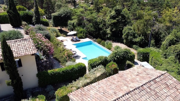 Une villa dotée d’une piscine, entourée d’une végétation luxuriante et surmontée d’un toit en tuiles.