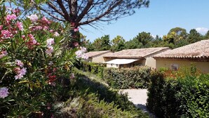 A row of traditional Mediterranean-style buildings with terracotta roofs, surrounded by lush greenery and flowering plants. - VILLA VERDI D AIR CONDITIONED APARTMENT WITH TERRACE AND PRIVATE GARDEN POOL (Montauroux)