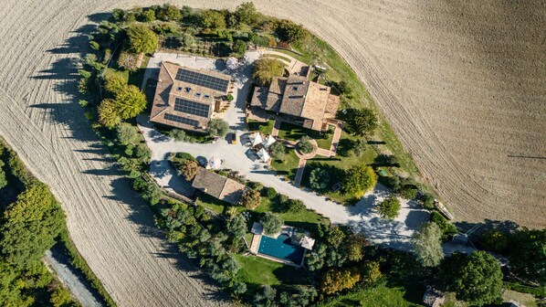 An aerial view of a residential area with multiple houses, a swimming pool, and surrounding greenery. - Deluxe Apartment The White Mulberry Tree Apartment (ARCEVIA)