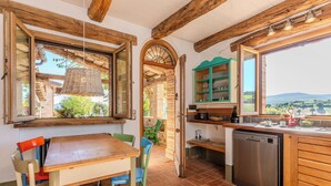Una cocina con una mesa de madera, sillas, lavavajillas y vistas al campo.