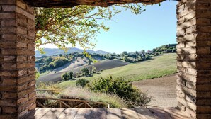 Un arco de piedra rústico enmarca una vista de colinas ondulantes y edificios lejanos.