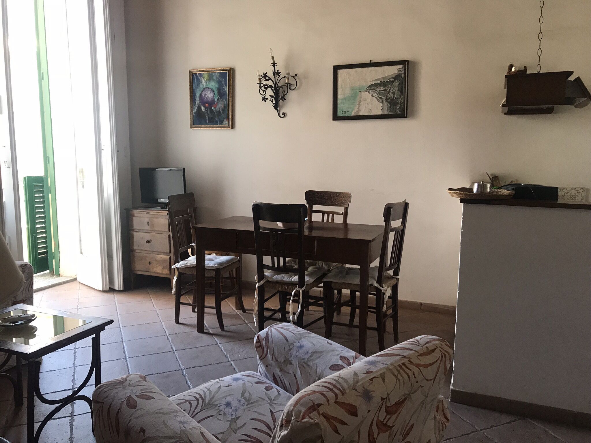 Un comedor con una mesa y sillas de madera, un televisor y obras de arte en la pared.