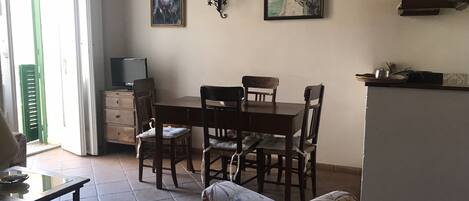 Un comedor con una mesa y sillas de madera, un televisor y obras de arte en la pared.