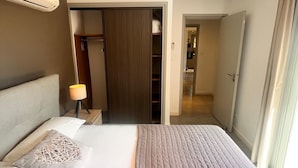 Ein Hotelzimmer mit Bett, Nachttischlampe, Kleiderschrank und Blick auf den Flur.