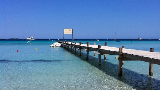 Eine Steg, der sich in klares türkisblaues Wasser erstreckt, mit einem Schild, auf dem 'Ribbit Dock' steht.