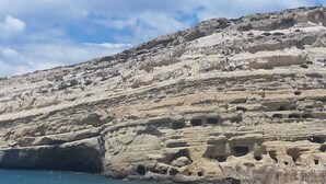 A coastal landscape with a rocky cliff featuring numerous caves and a sandy beach. - Julie's studio in Kokkini Hani, 2 mins walk to beach. Near famous theme parks!  (Kokkini Hani)