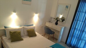 A neatly made bed with pillows, a desk with a chair, and a mirror. - Julie's studio in Kokkini Hani, 2 mins walk to beach. Near famous theme parks!  (Kokkini Hani)