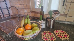 Uma bancada de cozinha com uma cesta de frutas, uma garrafa e um porta-utensílios.