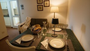 Mesa posta com pratos, talheres, copos e um abajur.