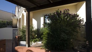 A courtyard with a large bush, a pergola, and a building with arches. - Apartment for 4 person with private garden  (San Pasquale)