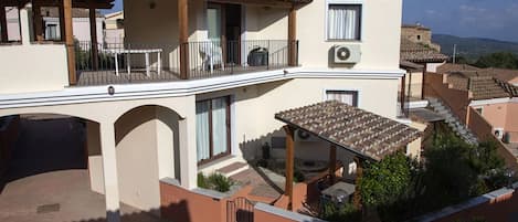 A two-story building with a balcony, a covered patio, and a view of the surrounding area.