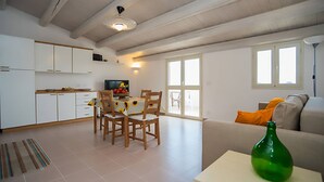 Un'ampia zona giorno con tavolo da pranzo, sedie, divano e televisione.