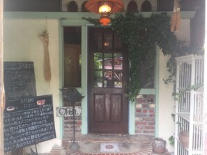 A rustic building entrance with a wooden door, a signboard with menu items, and a hanging lantern. - Auberge Booz Annex (Yamanakako)