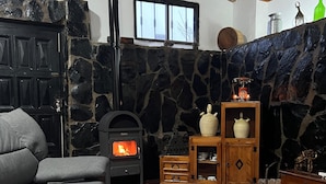 A cozy living room with a stone wall, a fireplace, a sofa, and a wooden table.
