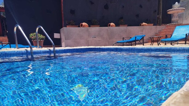 A swimming pool with clear blue water, a ladder, and lounge chairs.