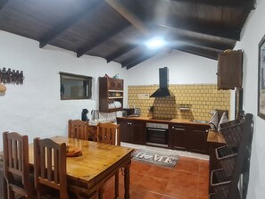 A cozy kitchen with wooden cabinets, a tiled backsplash, and a dining area with a wooden table and chairs. - Typical Canarian house with pool and wifi in the mountains of Telde. (Telde)