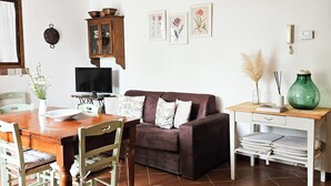 A living room with a brown leather sofa, a wooden dining table with chairs, a TV, and a cabinet. - WINDMILL apartment with private terrace (Empoli)