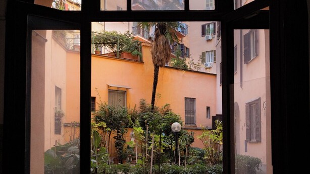 An arched doorway leading to a courtyard with potted plants and a street view. - Wonderful beautiful apartment in the heart of Rome (Esquilino Colosseum area) (Roma)
