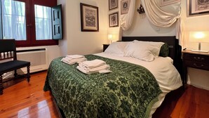A neatly made bed with a green patterned bedspread, a chair, and a bedside table with a lamp. - Spirit of 1512 - Exquisite taste in the heart of Alfama (Lisboa)
