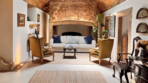 A cozy living room with a rustic brick ceiling, a white sofa, two armchairs, a coffee table, and various decorative items. - Spirit of 1512 - Exquisite taste in the heart of Alfama (Lisboa)