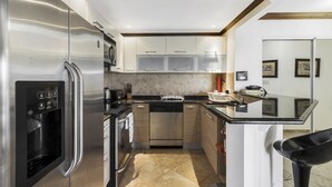 Een moderne keuken met roestvrijstalen apparatuur, een vaatwasser en een zwarte barkruk.