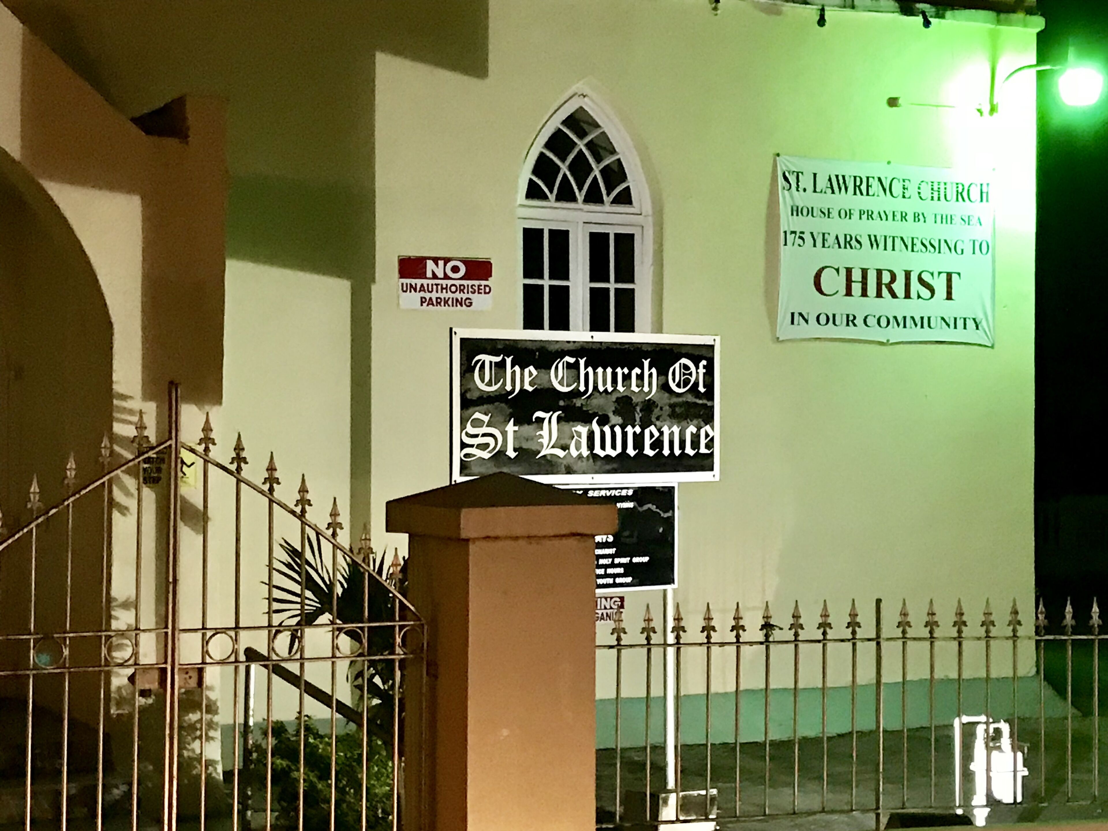 A church with a sign reading 'The Church Of St Lawrence' and another sign stating 'St Lawrence Church House of Prayer by the Sea 175 Years Witnessing to Christ in Our Community.'