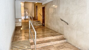 A modern hotel lobby with marble flooring, a metal handrail, and a staircase leading to another level. - Fast-E WiFi/On-St parking/Metro Hub @290m/Cafe Society Enclave. (Valencia)