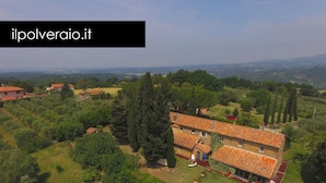 A large villa with multiple rooms and a spacious garden, surrounded by lush greenery and hills.
