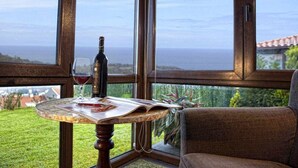 A table with a wine bottle and glass, a chair, and a view of the sea through large windows. - THE ERA OF SOMAO (Somado)