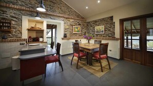 A kitchen with a stone wall, wooden dining table, and red chairs. - THE ERA OF SOMAO (Somado)