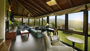 A cozy room with a wooden ceiling, large windows, a sofa, a table, and a view of the outdoors. - THE ERA OF SOMAO (Somado)